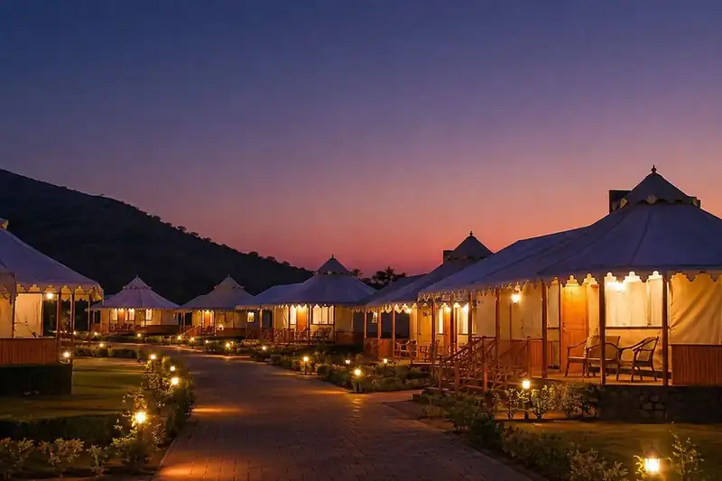 Row of illuminated luxury tent cottages along a lantern-lit pathway at dusk